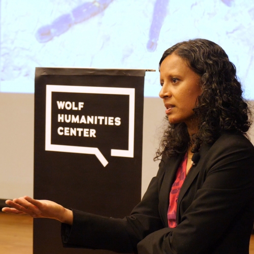 Lecturer Sanchita Balachandran in front of Wolf Humanities Center banner